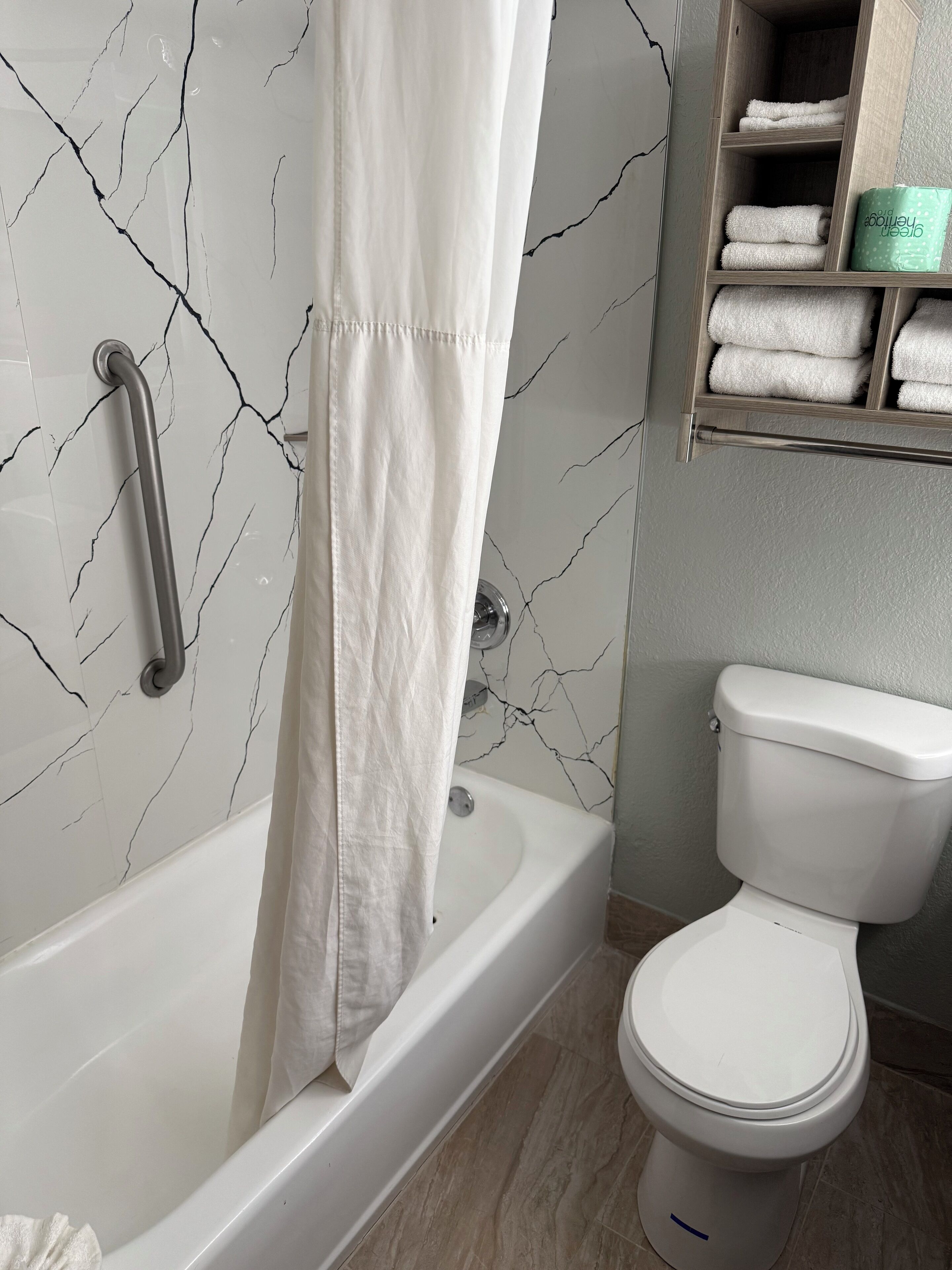 Een bad/douchecombinatie, een haardroger, handdoeken, zeep