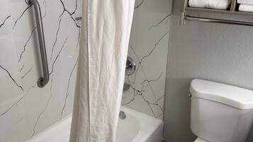 Een bad/douchecombinatie, een haardroger, handdoeken, zeep