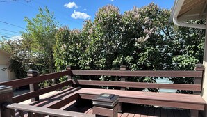 A wooden deck with a railing, a bench, and a small table.