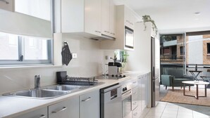 Una cocina moderna con electrodomésticos de acero inoxidable, un lavamanos doble y un comedor con mesa y sillas.