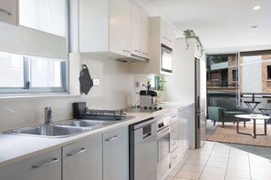 Eine moderne Küche mit Edelstahlgeräten, einer doppelten Spüle und einem Essbereich mit Tisch und Stühlen.