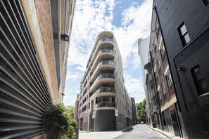A multi-story building with balconies, a gated entrance, and a clear sky. - Urban Oasis 2BR with Huge Deck & Secure Parking (Potts Point)