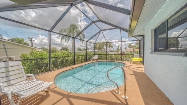 Piscina ao ar livre coberta com vista desobstruída da região circundante, incluindo um edifício branco e vegetação.