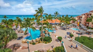 Un complexe hôtelier doté d’une grande piscine, de palmiers et offrant une vue sur l’océan.