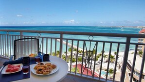 Un balcon avec une table préparée pour le petit-déjeuner, donnant sur une plage et l’océan.