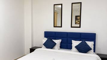 Une chambre d’hôtel comprenant un lit, deux tables de chevet, un ventilateur de plafond et deux miroirs fixés au mur.