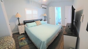 Un dormitorio con cama, mesitas de noche, televisión y escritorio.