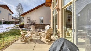 Une maison dotée d’un patio aménagé avec des fauteuils Adirondack et une porte vitrée donnant sur un espace extérieur abrité.