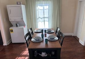 A dining area with a table set for four, a refrigerator, and a window with curtains. - Private bungalow close to LMU, ARH, Cumberland Gap (Middlesboro)
