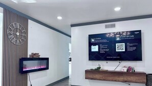 Un salon moderne avec un téléviseur à écran plat fixé au mur, une horloge décorative et une cheminée.