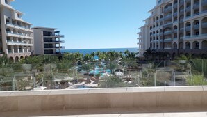 Un resort con una zona de piscina rodeada de palmeras y vistas despejadas al océano.