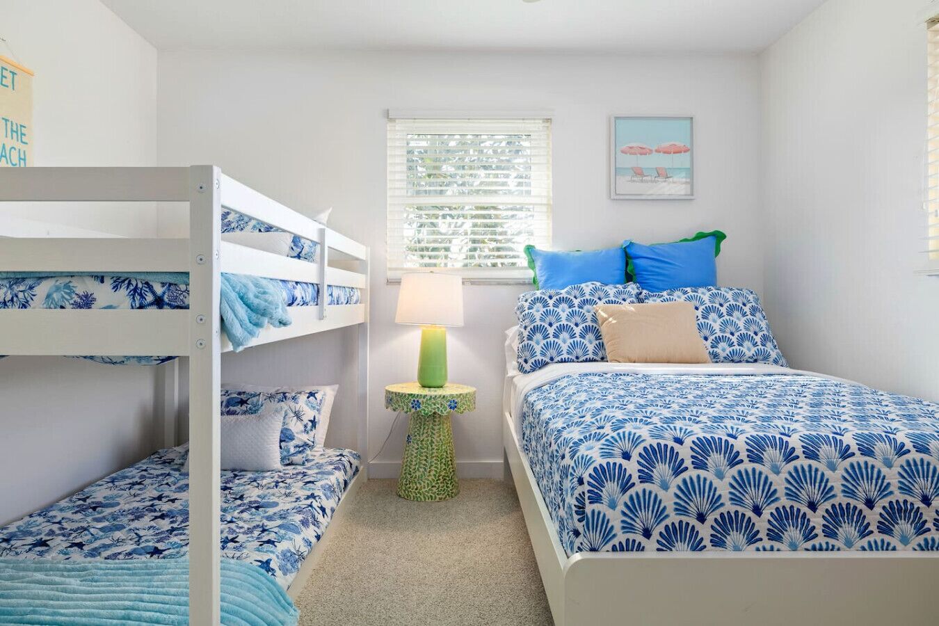 A bedroom with bunk beds, a bedside table with a lamp, and a bed with patterned bedding.