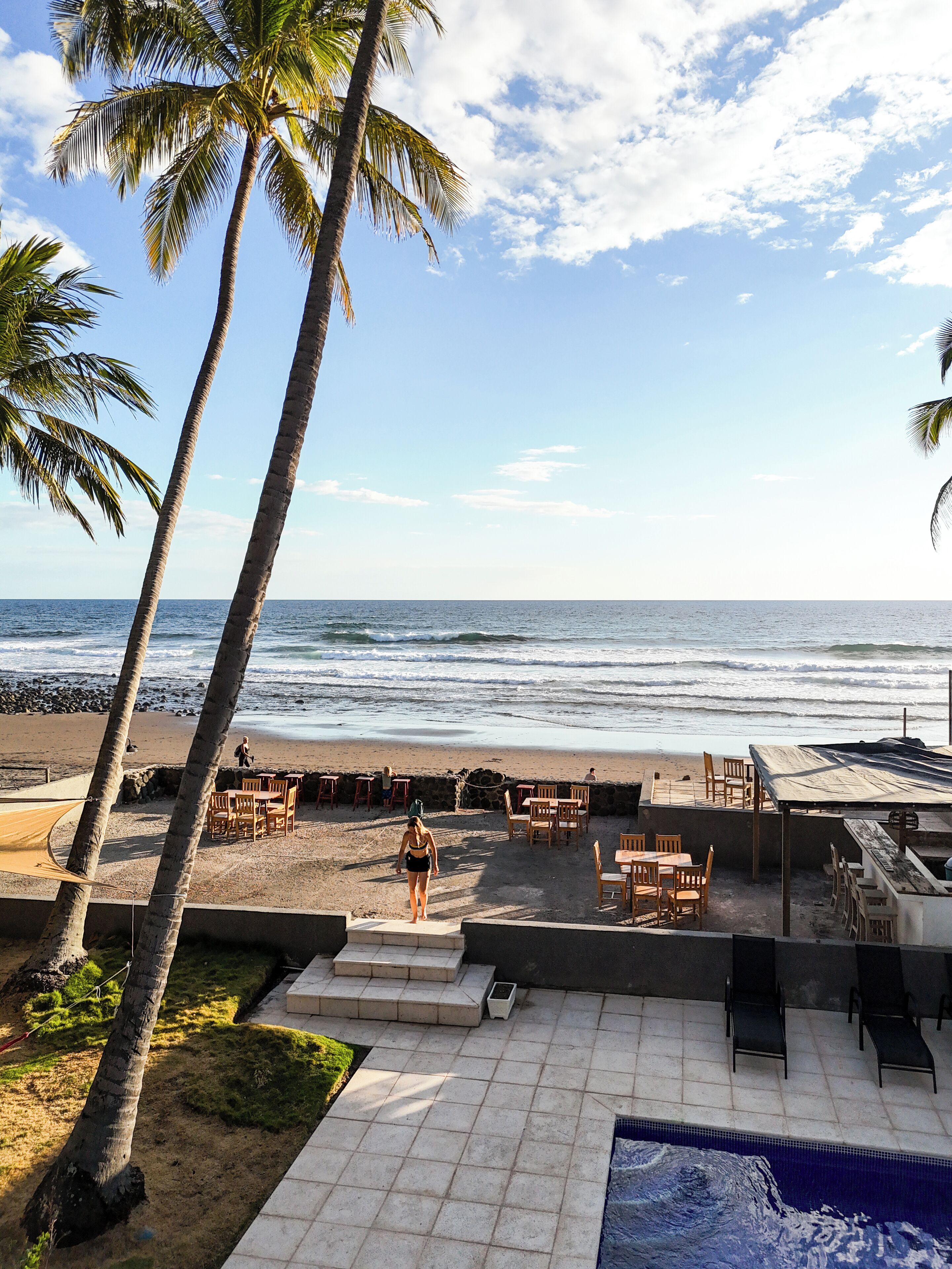 Um alpendre à beira-mar com área de estar externa, piscina e vista para o oceano.