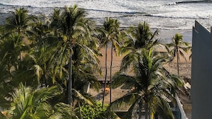 Vista sulla spiaggia con palme e cielo sereno.