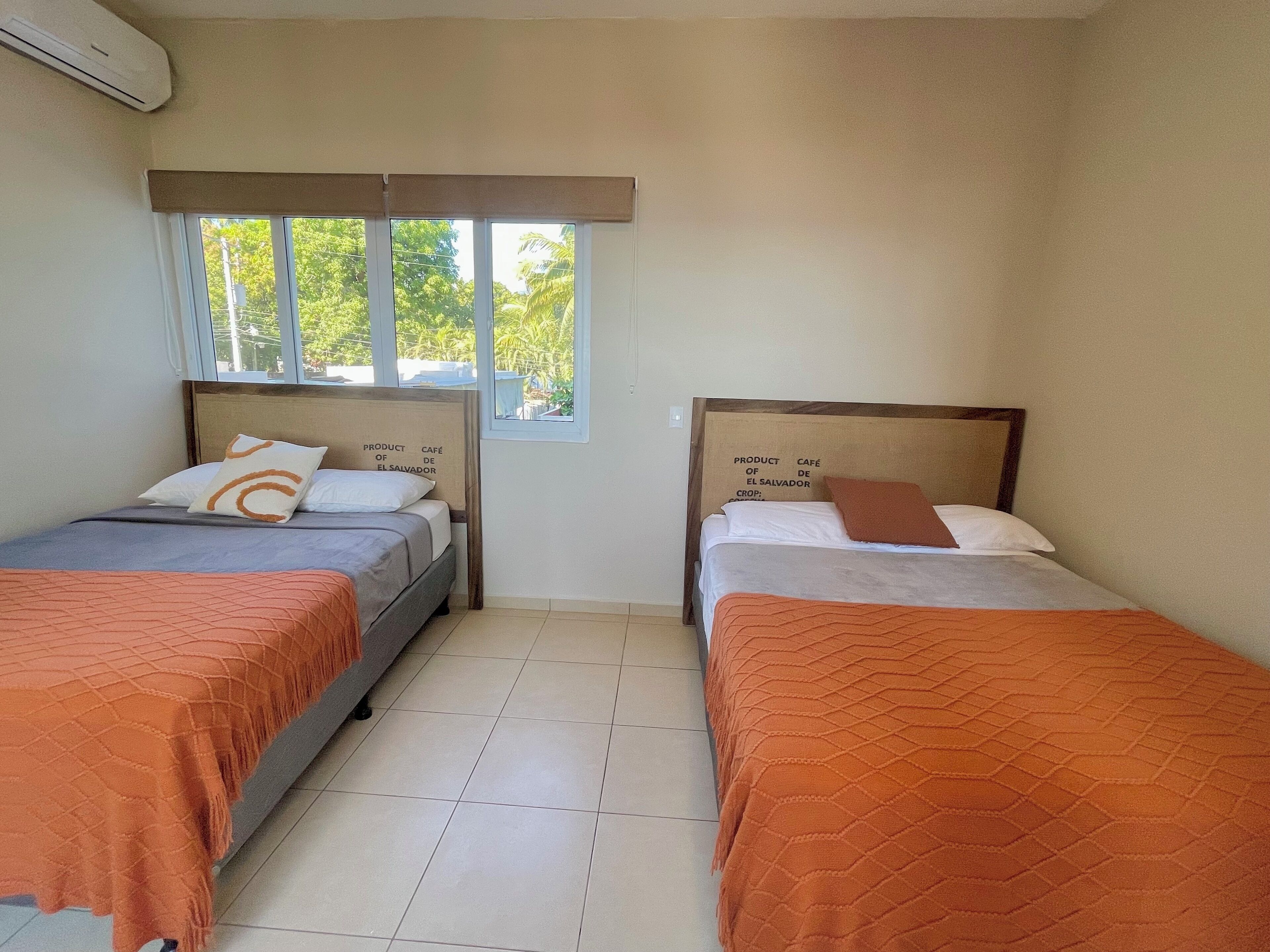 Una habitación de hotel con dos camas, cada una con cabecero de madera y una ventana.