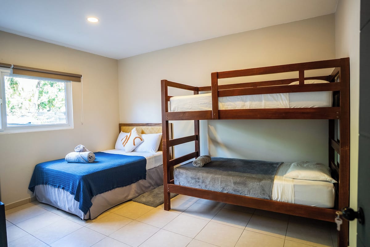 A room with two bunk beds, a window with blinds, and a door.