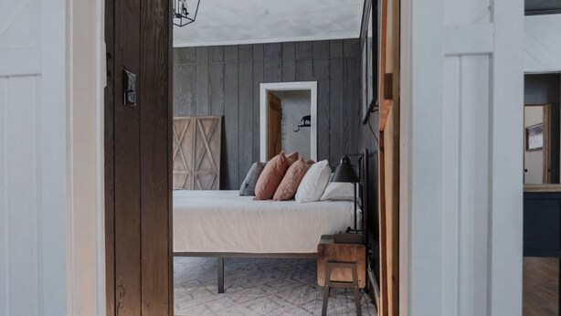 A bedroom with a bed, bedside table, and a wooden headboard. - Charming Cabin Hideaway, Peaceful Woodland Escape (Williamston)