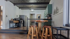 A kitchen with wooden stools, a bar counter, and a dining table. - Charming Cabin Hideaway, Peaceful Woodland Escape (Williamston)
