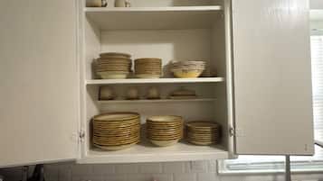 Cocina con gabinetes blancos, pileta de acero inoxidable y escurreplatos.