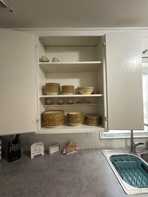 A kitchen with white cabinets, a stainless steel sink, and a dish drying rack.