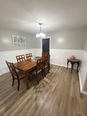 A dining area with a wooden table and chairs, a hanging light fixture, and a painting on the wall. - Quaint 3-bedroom house with AC in welcoming Wichita (Wichita)