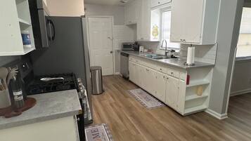 A kitchen with white cabinets, a stove, and a dishwasher.