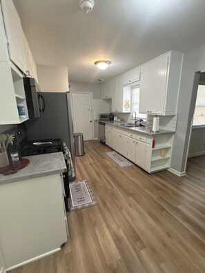 A kitchen with white cabinets, a stove, and a dishwasher. - Quaint 3-bedroom house with AC in welcoming Wichita (Wichita)