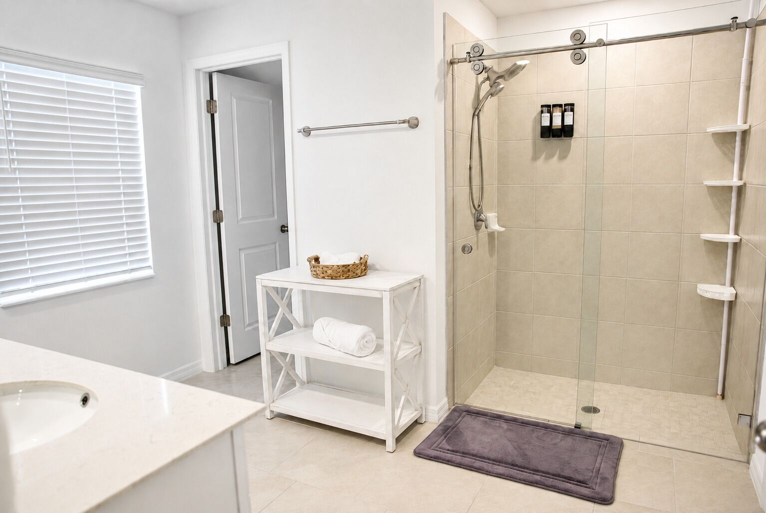 A bathroom with a shower, a sink, a toilet, and a towel rack.