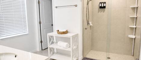 A bathroom with a shower, a sink, a toilet, and a towel rack.