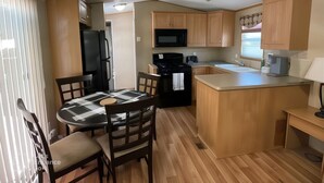 Una cocina compacta con armarios de madera, un refrigerador negro, un microondas y un lavabo.