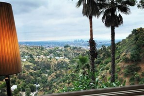 A view from a balcony overlooking a cityscape with palm trees in the foreground. - STUDIO 1080 HOLLYWOOD: Jetliner DTLA Views • Private Hillside Studio • King Bed (Los Angeles)