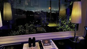 Ein Zimmer mit Blick auf die Stadt, ein Schreibtisch mit Fernglas, ein sternförmiges Schild und eine Lampe.