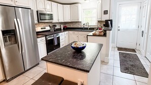 A modern kitchen with white cabinets, stainless steel appliances, and a dark countertop. - Charming Historic home steps away from downtown (Bath)