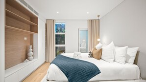 Un dormitorio moderno con una cama grande, un armario empotrado, una ventana con vistas y una mesita de noche con lámpara.