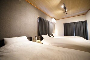 A hotel room with two beds, a ceiling fan, and a nightstand with a lamp. - Route 99 Miyagino (Hakone)