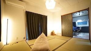 A traditional Japanese room with tatami flooring, a shoji screen, and a modern kitchenette visible through an open door. - Route 99 Miyagino (Hakone)