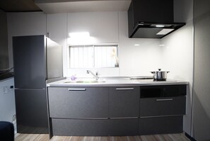 A modern kitchen with a built-in refrigerator, a sink with a faucet, and a window above the counter. - Route 99 Miyagino (Hakone)