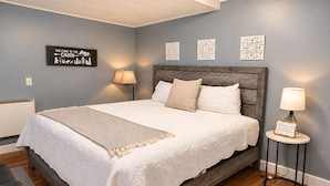 Une chambre à coucher avec un lit, des lampes de chevet, un panneau mural et des œuvres d’art décoratives accrochées au mur.