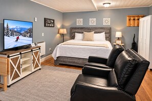 A bedroom with a bed, a television on a wooden cabinet, a black leather sofa, and a wooden cabinet with drawers. - Overlook Condo 21-C Studio ~ Off Mountain ~ 6 miles to Snowshoe Mountaintop Village (Slatyfork)