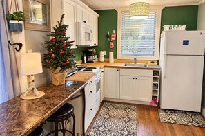 A kitchen with white cabinets, a stove, a sink, and a refrigerator. - Overlook Condo 21-C Studio ~ Off Mountain ~ 6 miles to Snowshoe Mountaintop Village (Slatyfork)