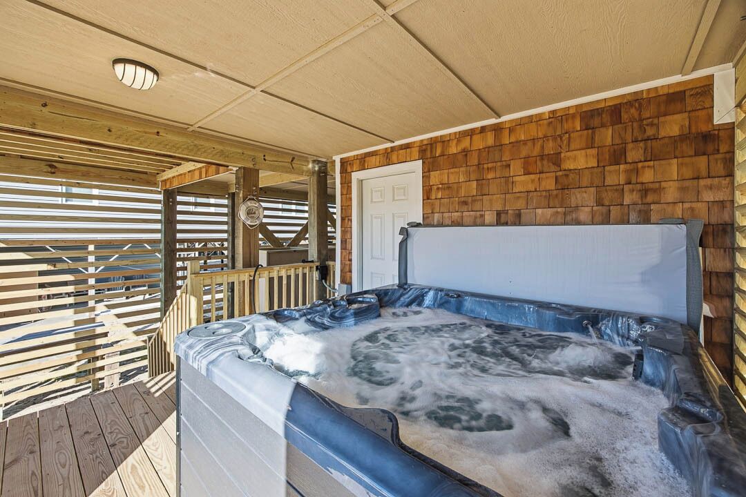 A hot tub with a wooden deck and a wooden wall.