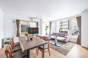 A modern living room with a dining area, a flat-screen TV, and a sofa. - SAPPORO STAY HIRAGISHI 201 (Sapporo)