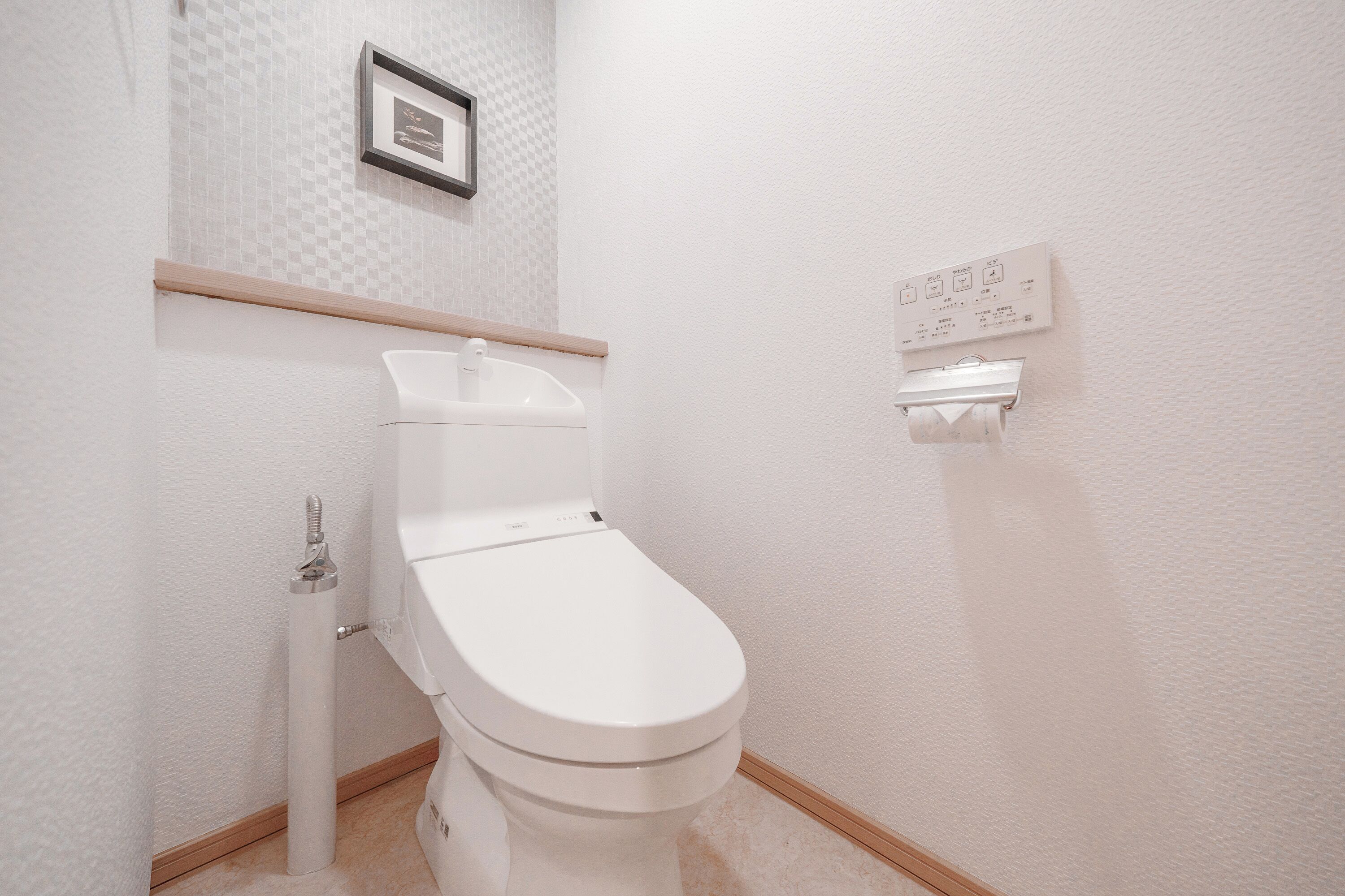 A white toilet with a wall-mounted flush handle and a toilet paper holder.