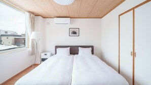 Ein Hotelzimmer mit einem großen Bett, einem Fenster mit Vorhängen, einer Deckenleuchte und einem gerahmten Bild an der Wand.