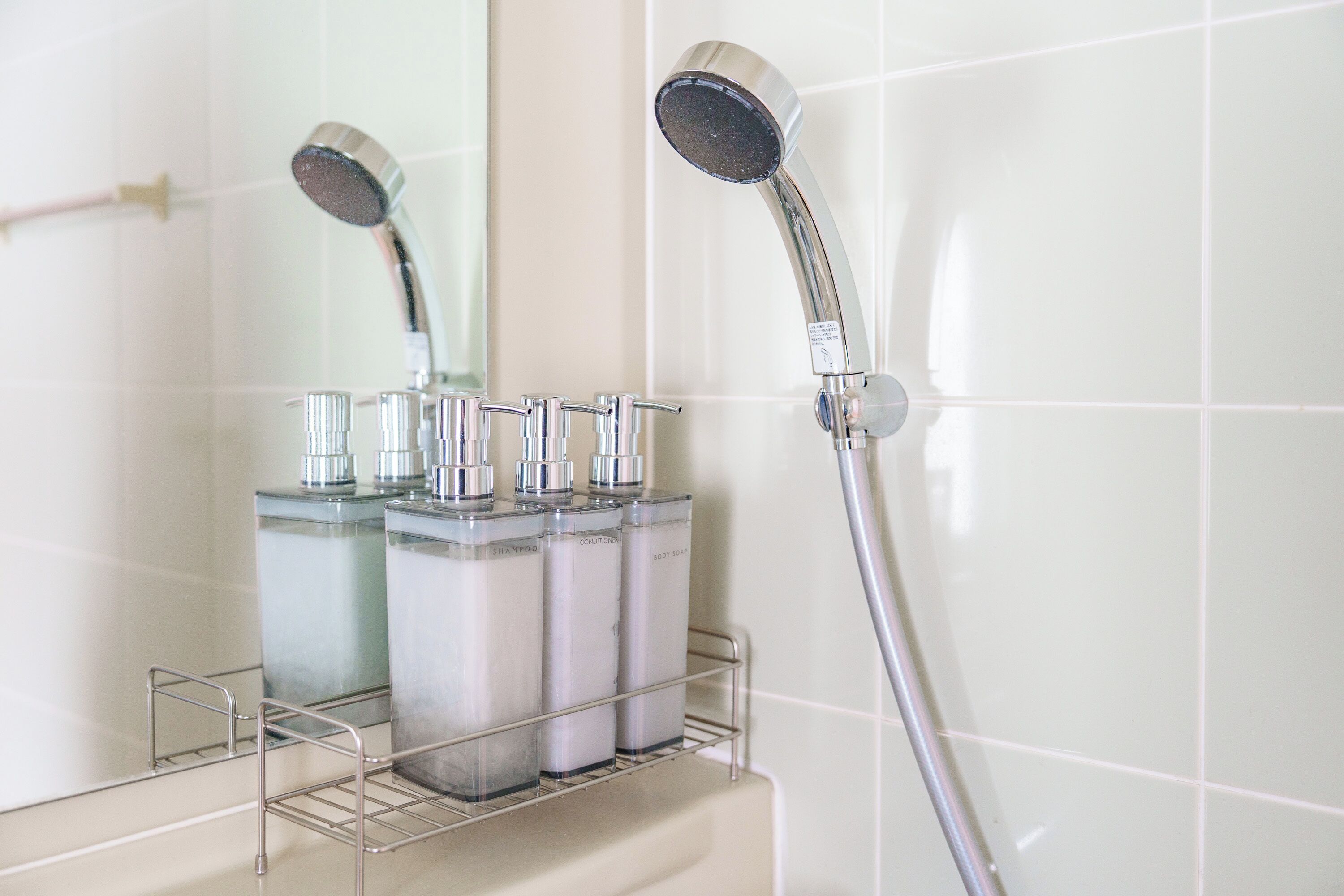 A bathroom with a shower, a mirror, and a shelf with toiletries.