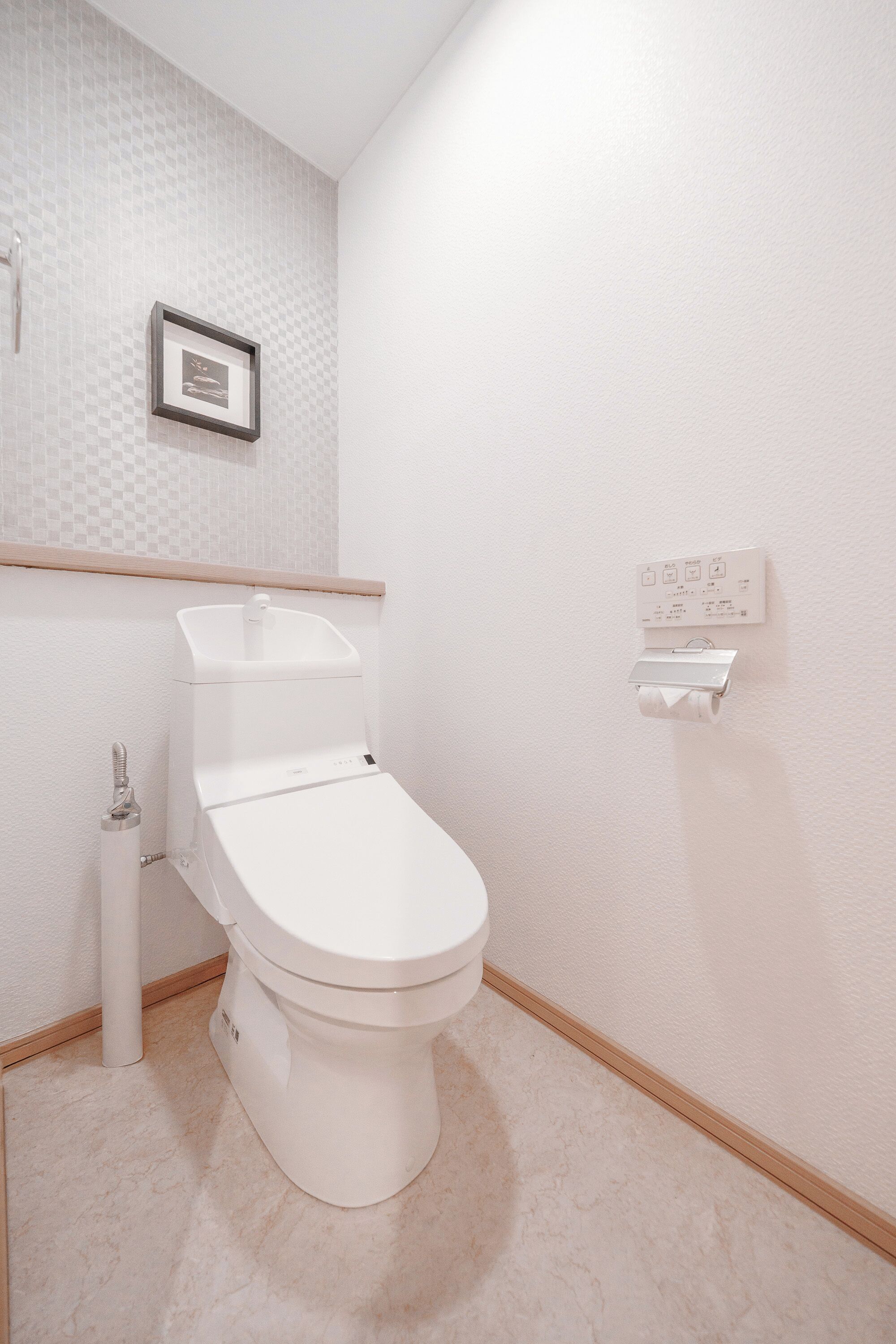 A modern bathroom with a toilet, a wall-mounted sink, and a toilet paper holder.