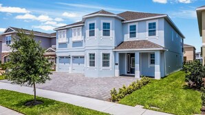A two-story residential building with a central entrance, multiple garage doors, and a well-maintained lawn. - The GemStone Retreat (Kissimmee)