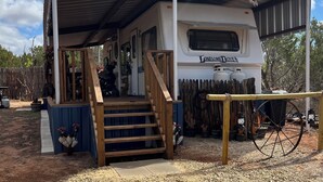 Un camper con un portico coperto, una scala e una carriola.