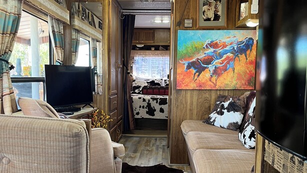 Een gezellig interieur van een camper, met een televisie, zithoek en een kussen van runderleer.