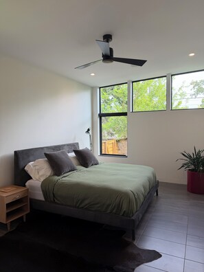 A modern bedroom with a bed, nightstand, and a ceiling fan. - Architect-Designed Modern Home in University Heights, minutes walk from Kinnick (Iowa City)